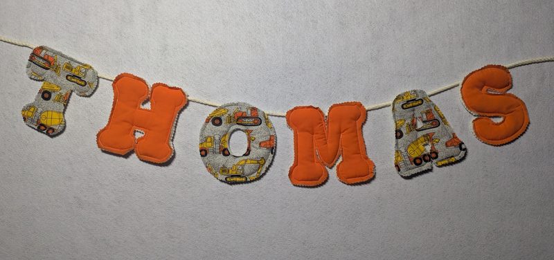 Handmade memory bunting by Needle and Nest spelling THOMAS in orange and construction vehicle print fabric